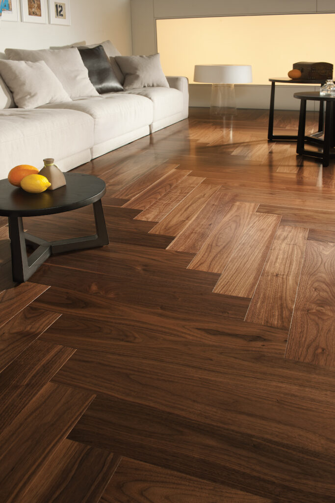 Chevron-patterned SPC vinyl flooring in light oak tones with beveled edges and matte finish.